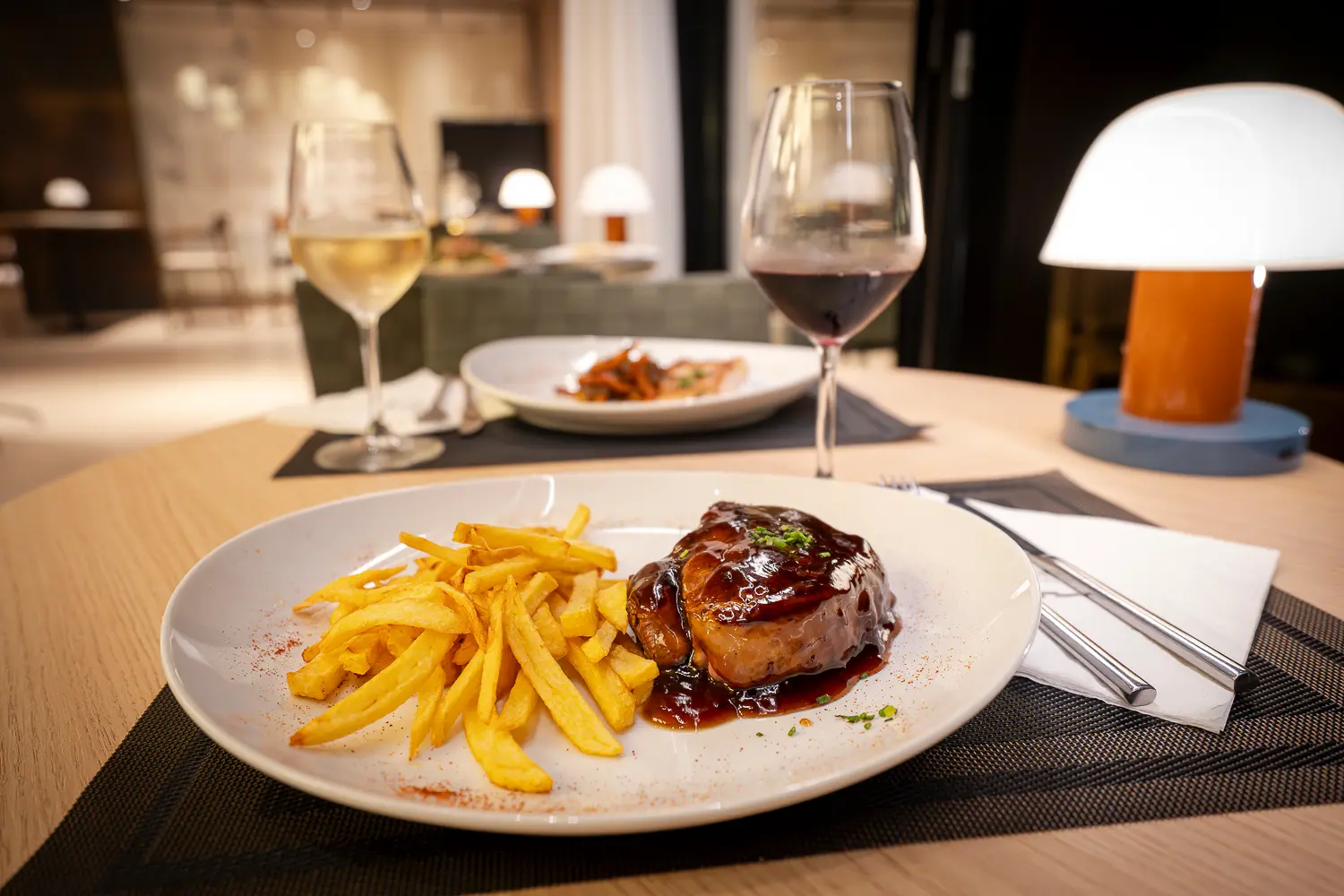 Carne en salsa con patatas fritas y vino en restaurante del hotel zenit ambiente elegante