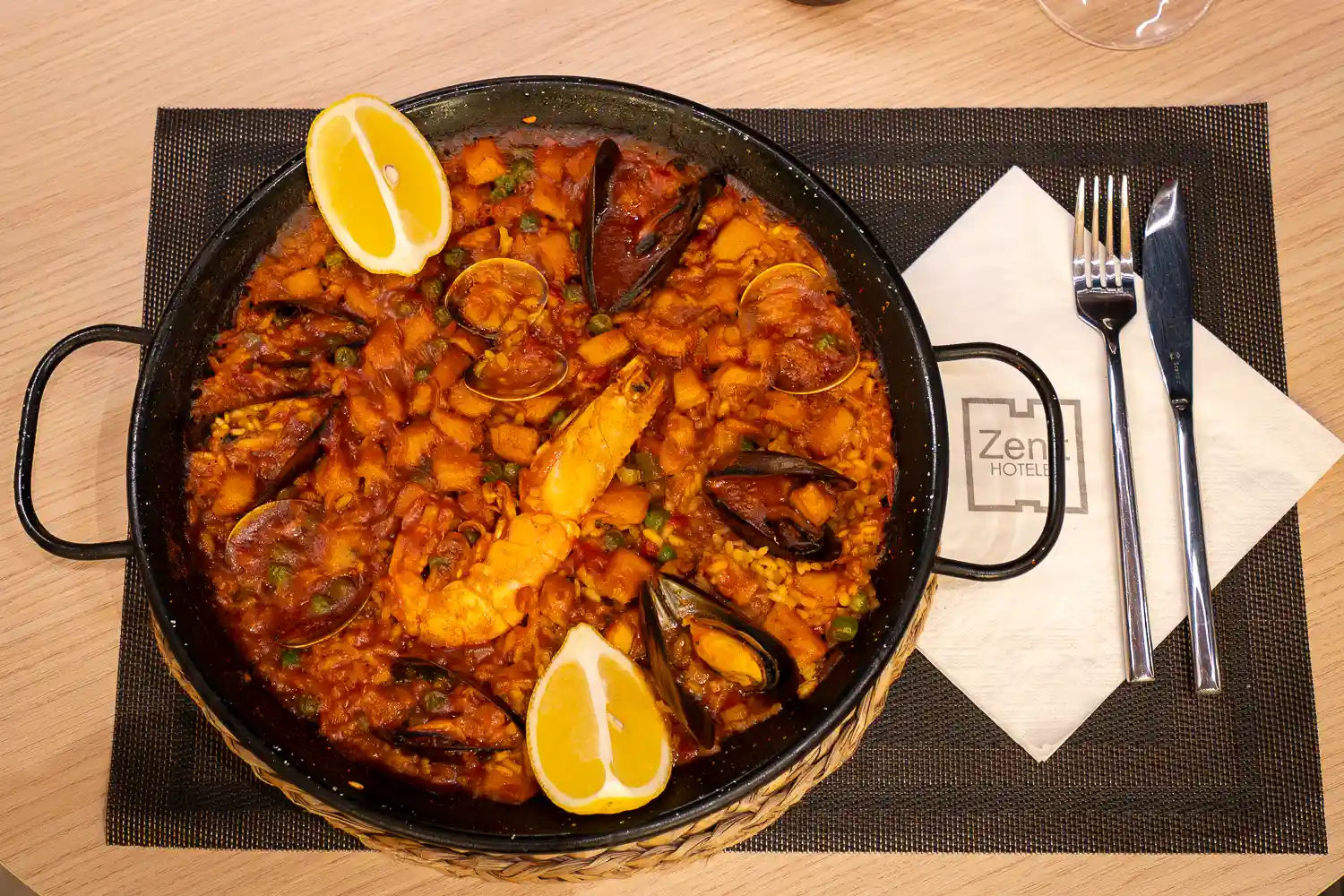 Paella de mariscos en restaurante hotel zenit con mejillones gamba y limon presentacion ambientada