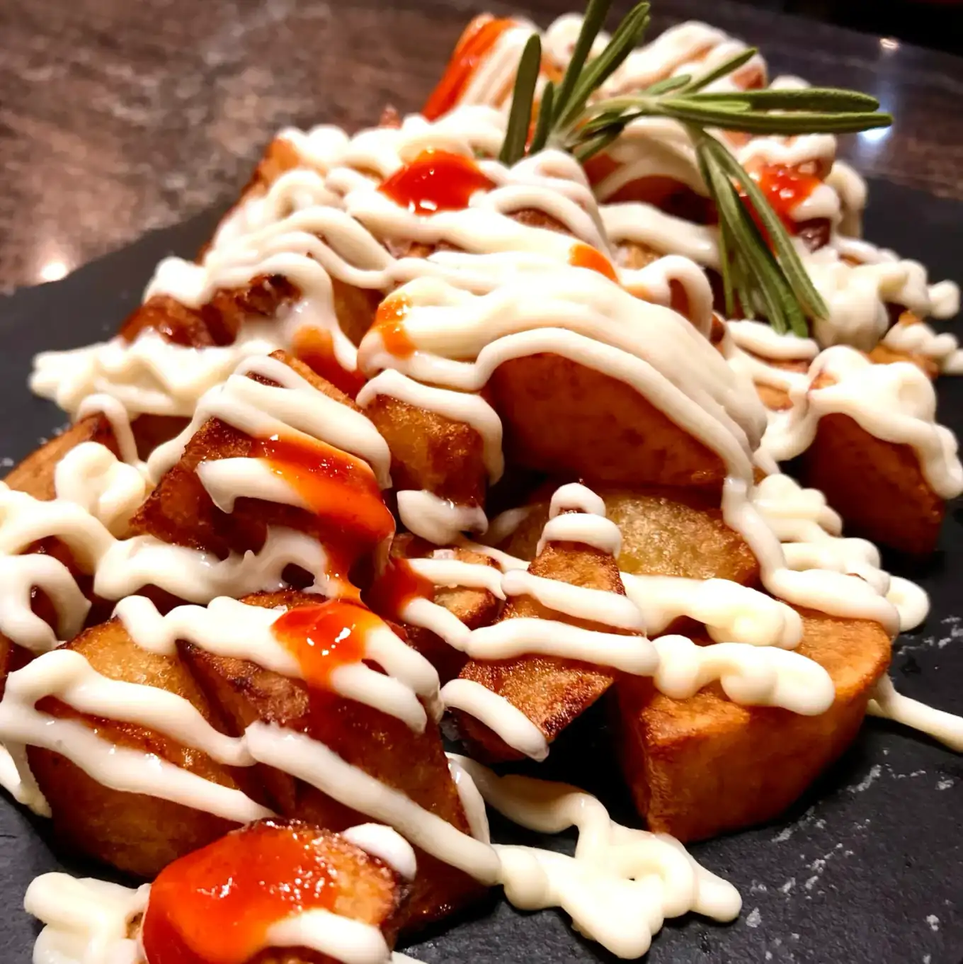 Patatas bravas servidas en Cal Tete, restaurante mediterráneo en Sant Martí, Barcelona, especialidad en tapas variadas.