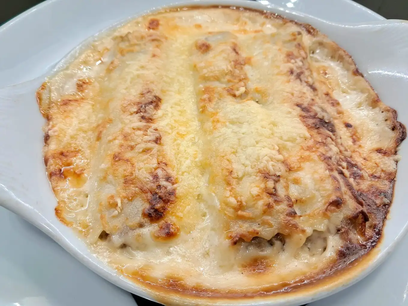 Canelones gratinados en Samuga, restaurante de cocina catalana casera en Sant Llorenç de la Muga, Girona. Especialidad mediterránea con raciones abundantes.
