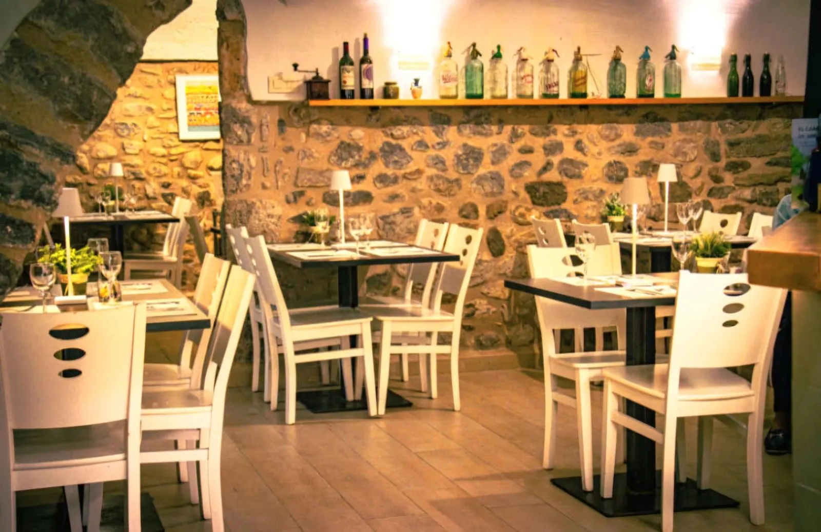 Sala interior de Restaurant Samuga en Sant Llorenç de la Muga, Girona, con paredes de piedra vista, mesas montadas y ambiente acogedor
