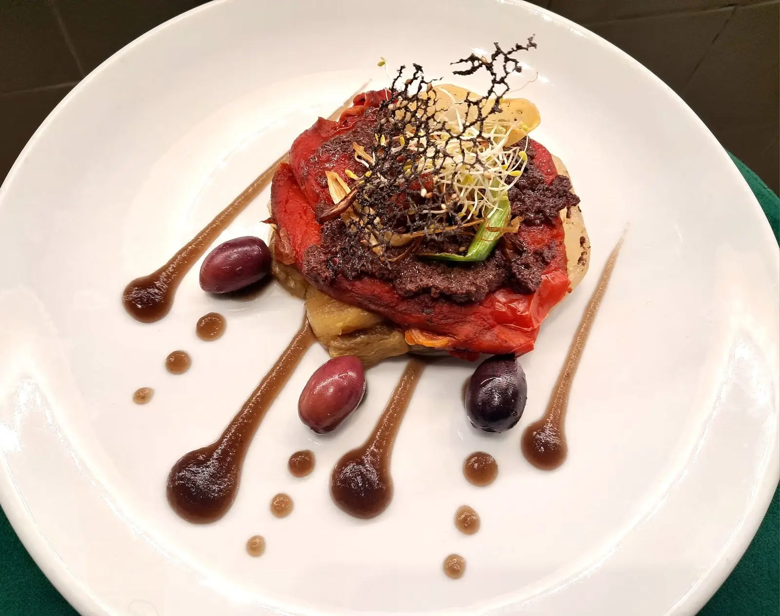 Timbal de verduras escalivadas con olivada y brotes sobre plato blanco en Restaurant Samuga, cocina catalana casera en Sant Llorenç de la Muga, Girona