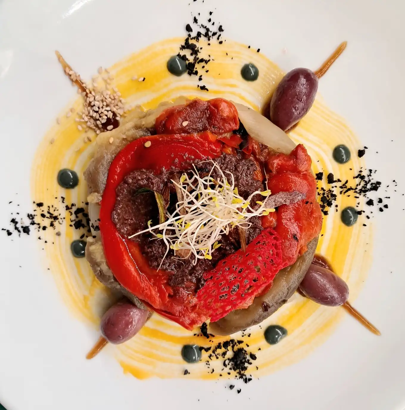 Plato vegetal con pimiento rojo asado, aceitunas moradas y brotes sobre crema en Restaurant Samuga, Sant Llorenç de la Muga (Girona)