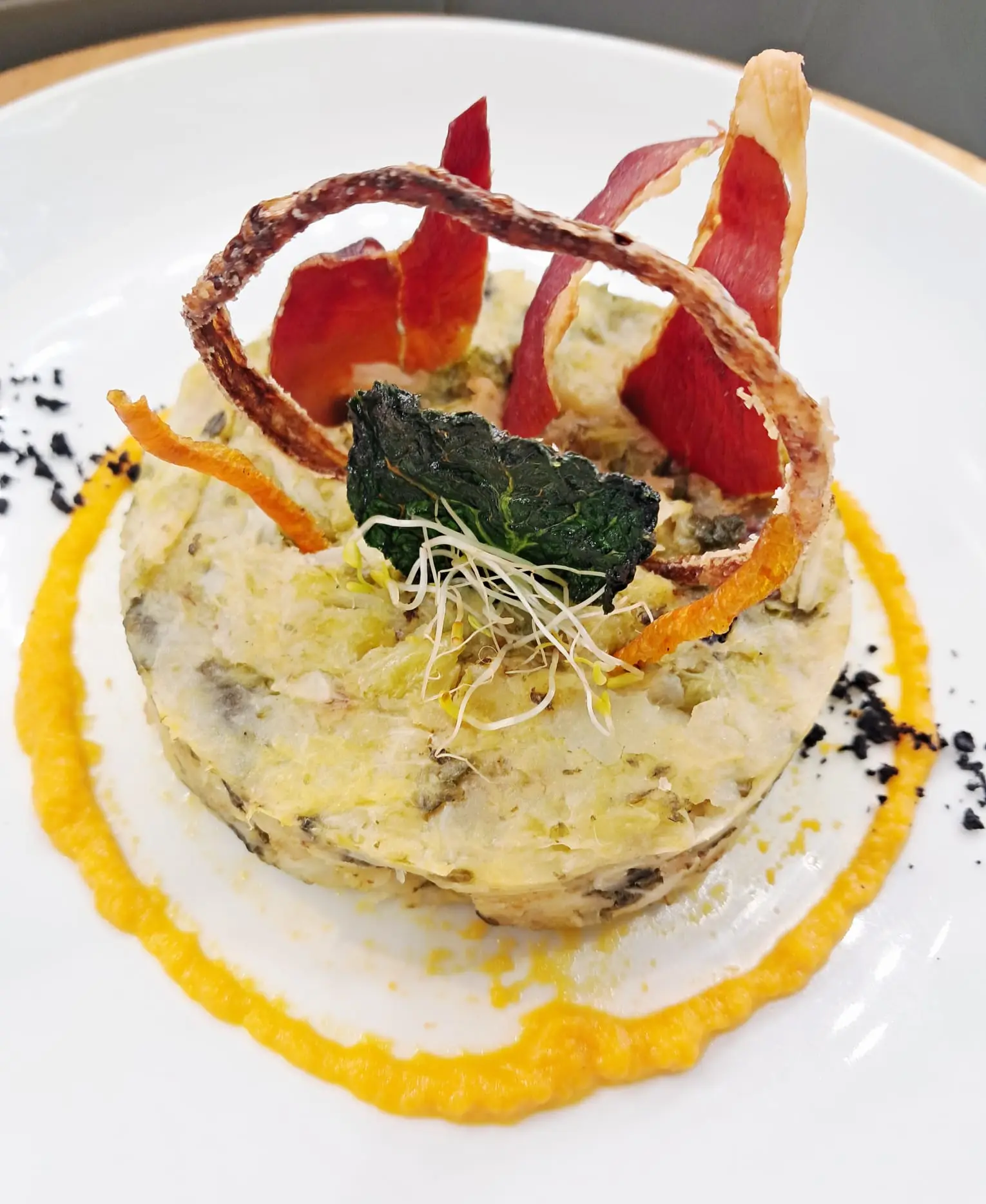 Timbal de patata y verduras con chips crujientes y brotes sobre crema de zanahoria en Restaurant Samuga, Sant Llorenç de la Muga (Girona)