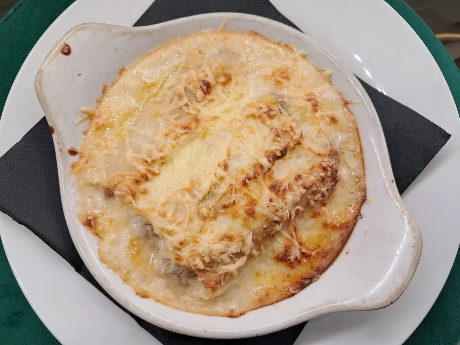 Lasaña casera gratinada con queso servida en fuente de cerámica en Restaurant Samuga, Sant Llorenç de la Muga, Girona