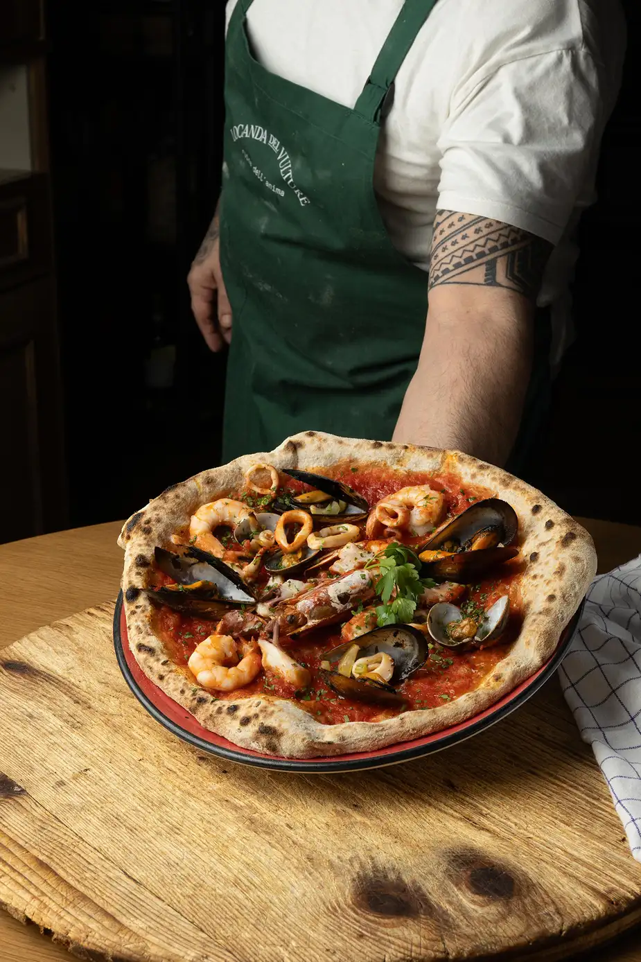 Pizza del xef Saverio en Locanda del Vulture, auténtica cocina italiana en Sant Martí, Barcelona, con mariscos frescos y masa artesanal.