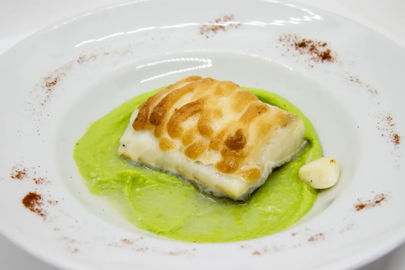 Bacalao gratinado sobre puré de guisantes en Agumas, restaurante de cocina mediterránea en Albanyà, Girona.