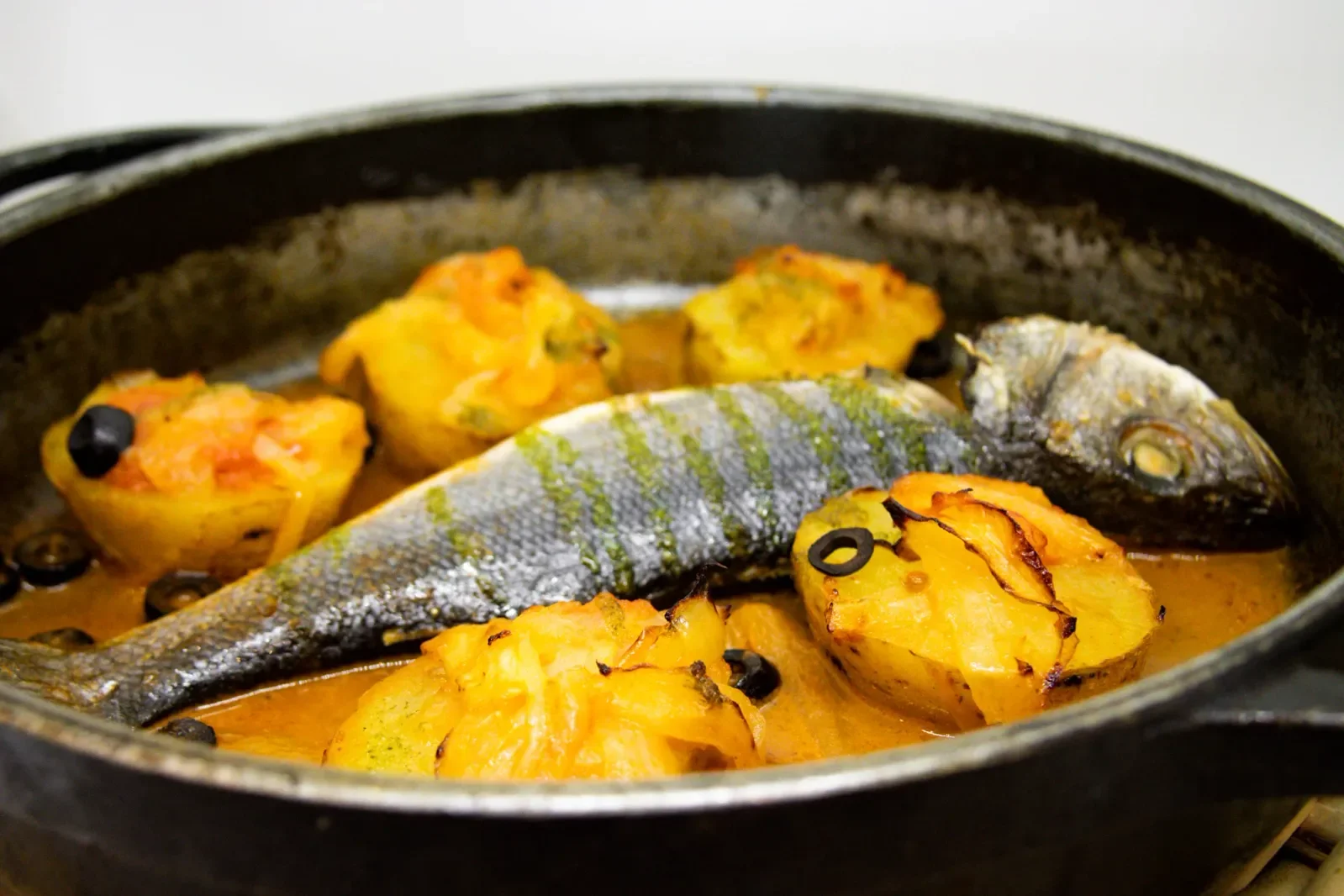 Dorada al horno con patatas y aceitunas en Agumas, cocina mediterránea en Albanyà, Girona. Ideal para disfrutar en un entorno natural excepcional.
