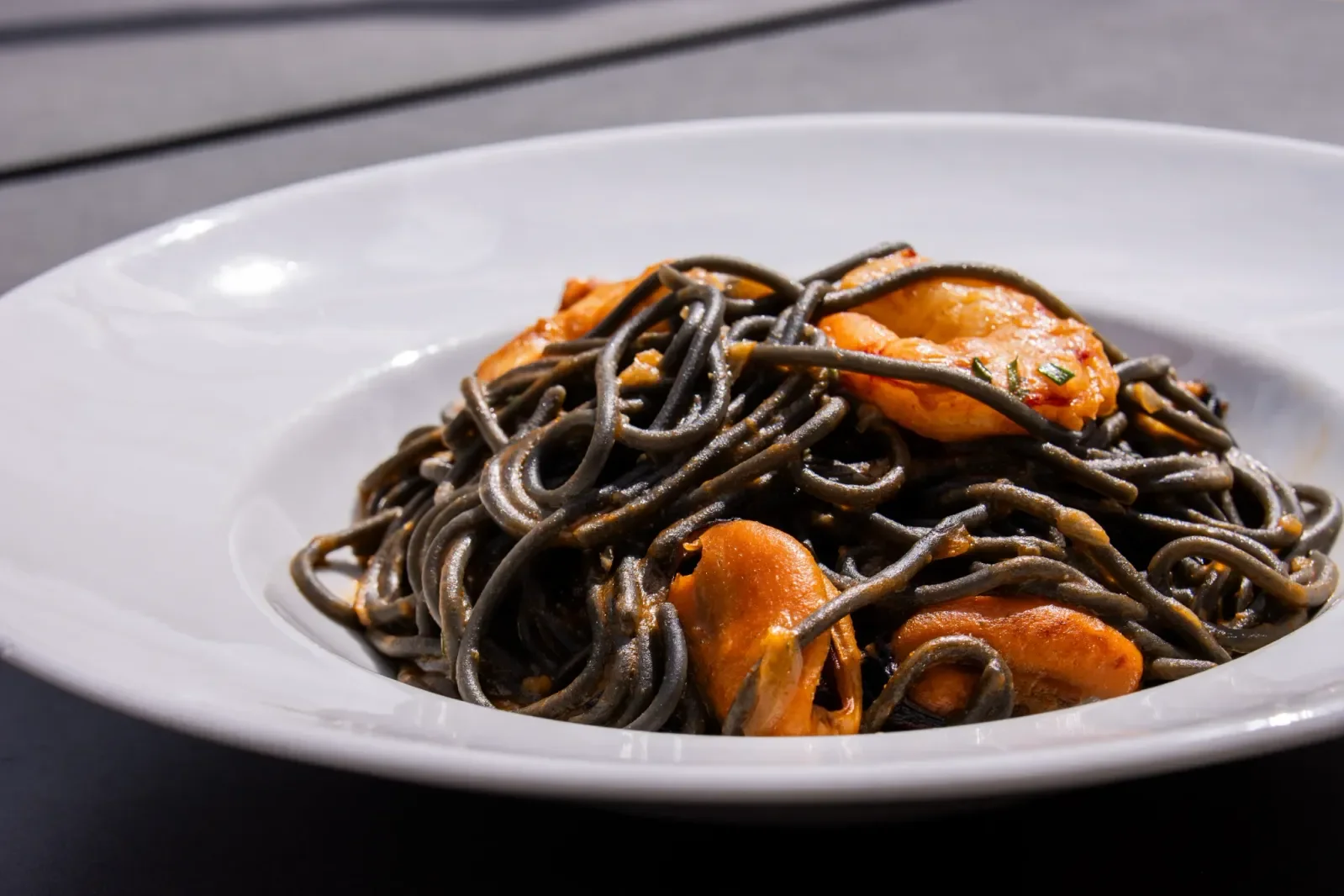 Espaguetis negros con mariscos en Agumas, restaurante de cocina mediterránea en Albanyà, Girona. Disfruta de este plato en el corazón de la Alta Garrotxa.