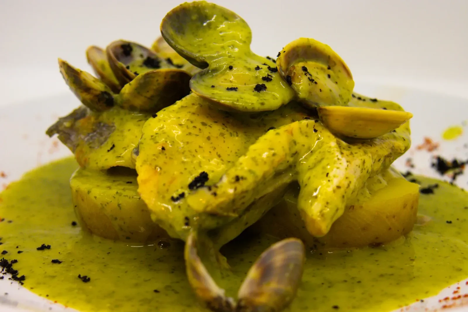 Pollo con almejas en salsa verde servido en Agumas, restaurante de cocina mediterránea en Albanyà, Girona. Disfruta de este plato en un entorno natural excepcional.