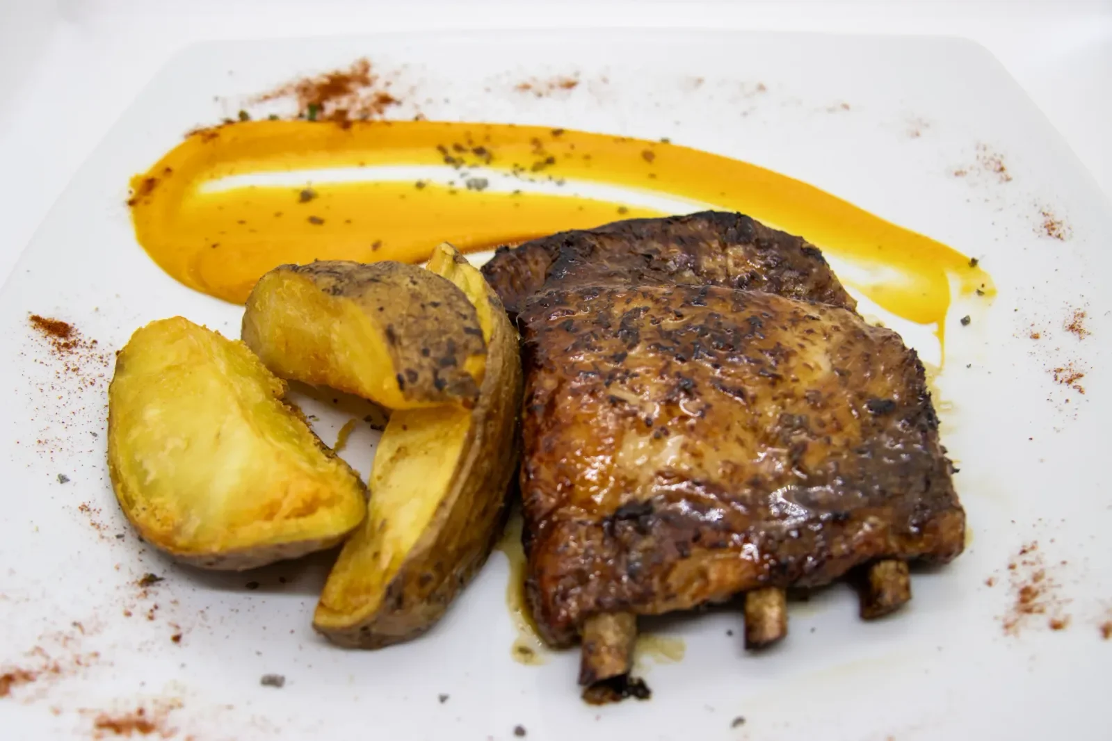 Costillas asadas con patatas en Agumas, restaurante de cocina mediterránea en Albanyà, Girona. Disfruta de este plato en un entorno natural excepcional.
