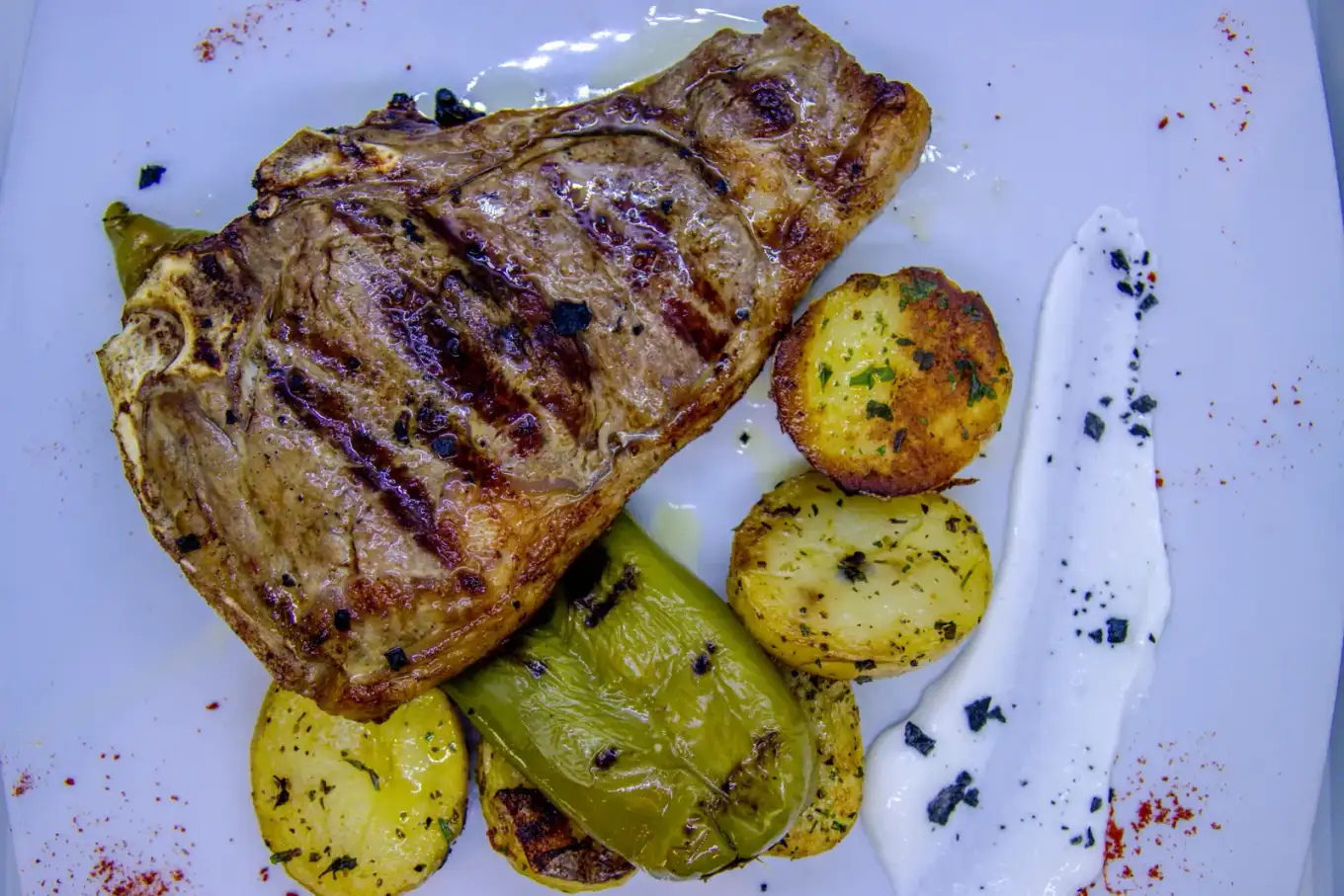 Chuleta a la parrilla con guarnición de patatas y pimientos en Agumas, cocina mediterránea en Albanyà, Girona.