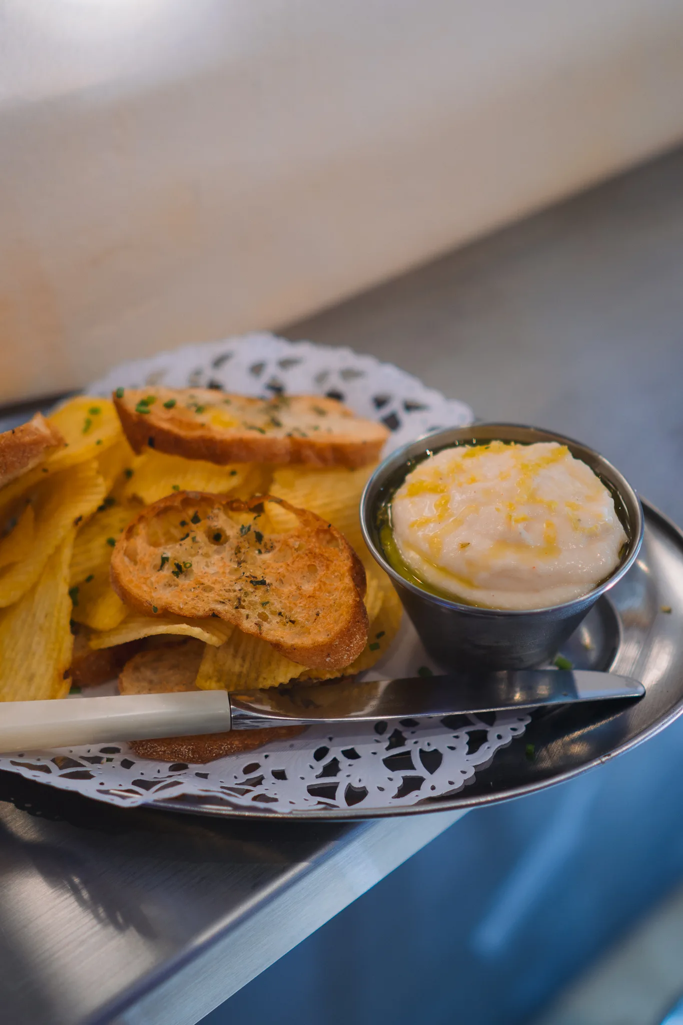 Dip de ceba francesa en Dreamboat Bar & Deli, Sant Martí, Barcelona, acompañado de tostadas y patatas, ideal para disfrutar en un ambiente animado.