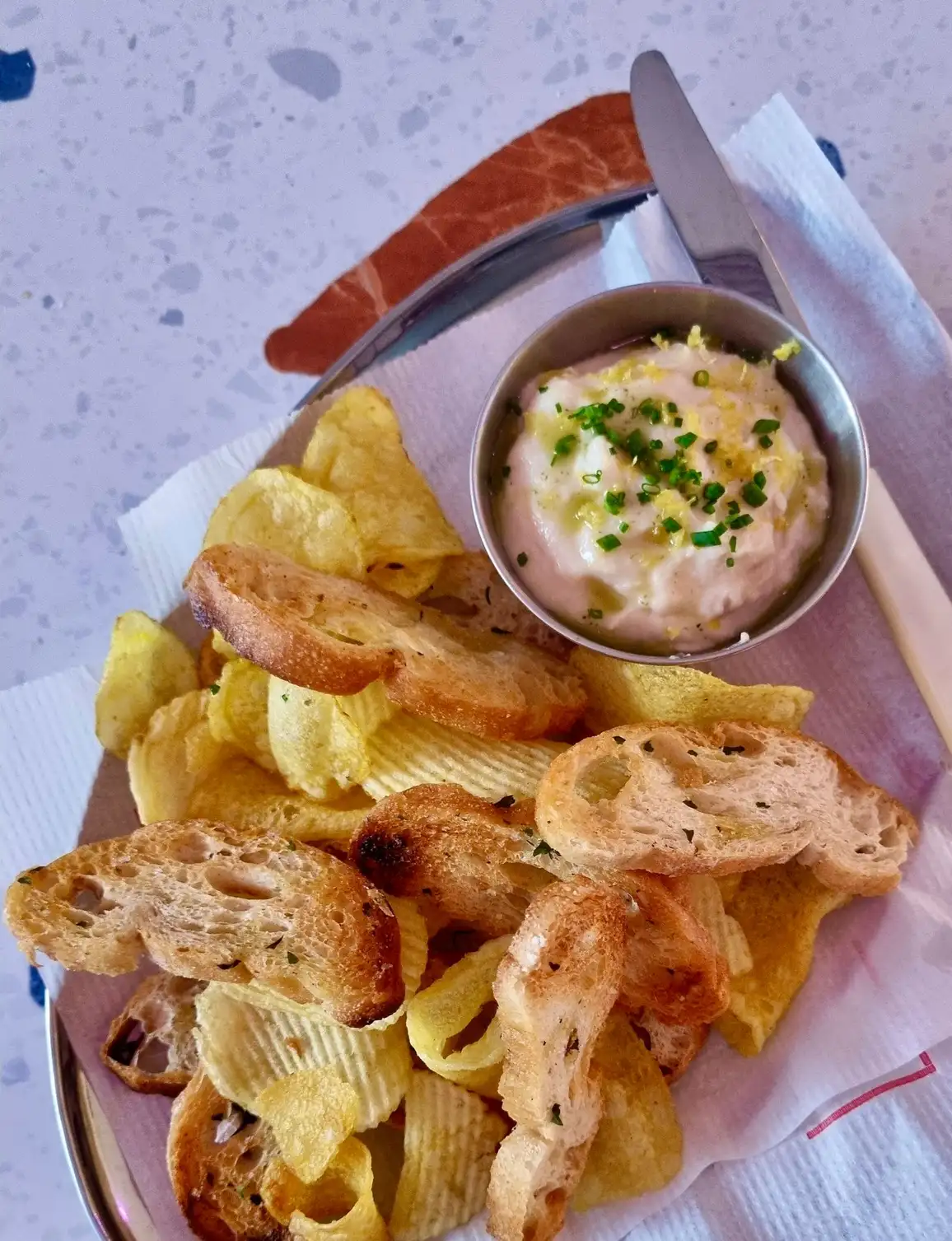Dip de ceba francesa en Dreamboat Bar & Deli, Sant Martí, Barcelona, acompañado de chips y pan crujiente, ideal para compartir en un ambiente amigable.