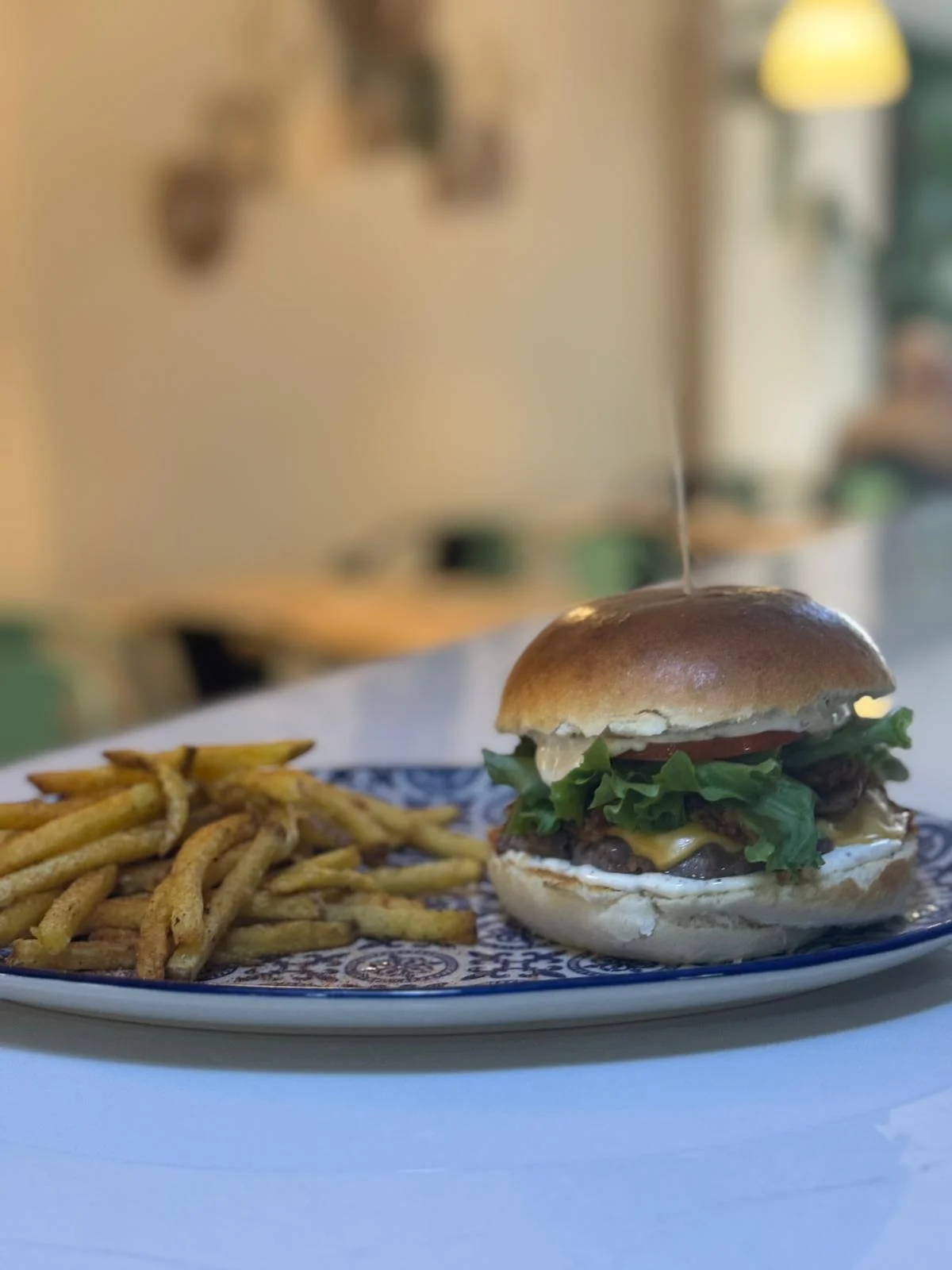 Hamburguesa con patatas fritas en Nomada Restaurant & Brunch, especialidad en desayunos y brunch en Figueres. Disfruta de un ambiente bohemio en el centro de la ciudad.