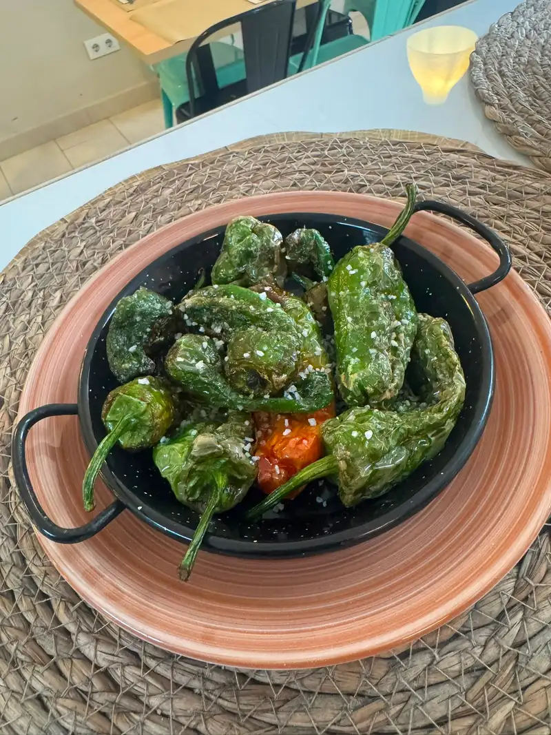 Pimientos del padrón asados con sal gruesa servidos en cazuela negra en Nomada Restaurant & Brunch en Figueres, Girona