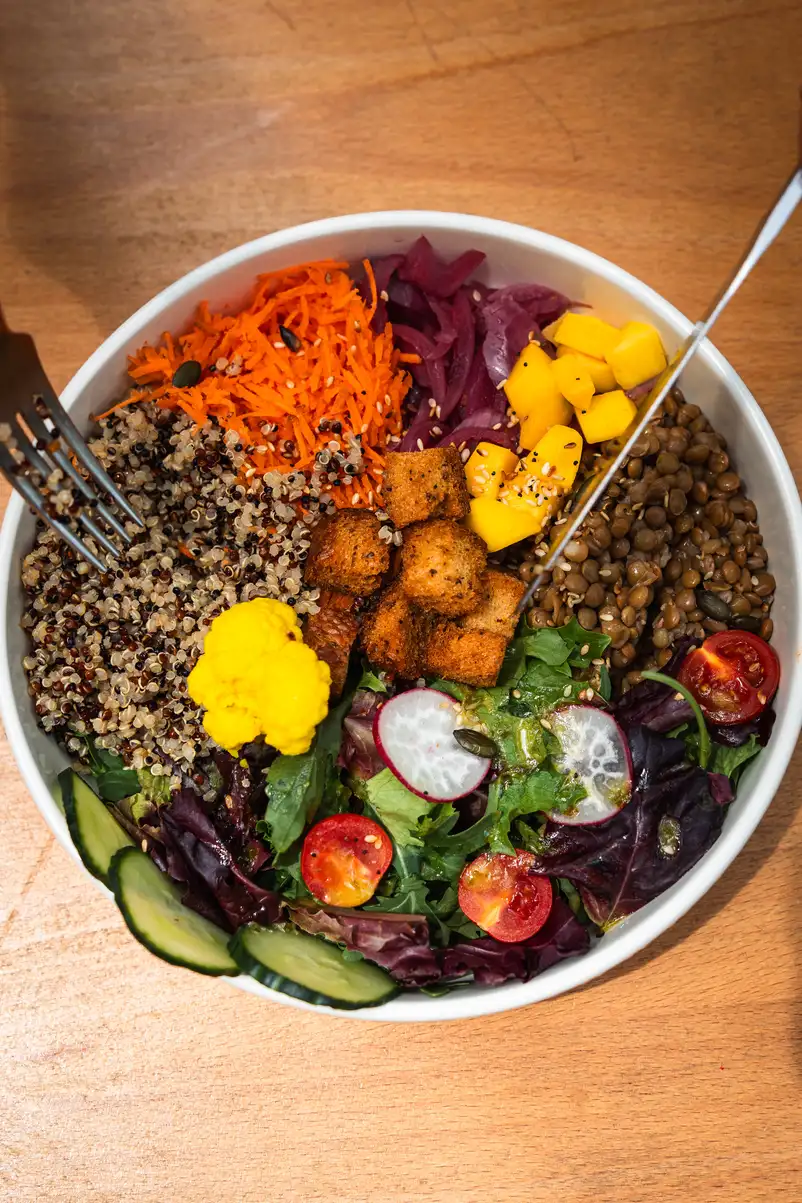 Bol de ensalada de quinoa, lentejas y mango en Morgentau, restaurante vegano en Sant Martí, Barcelona, ideal para un brunch saludable.
