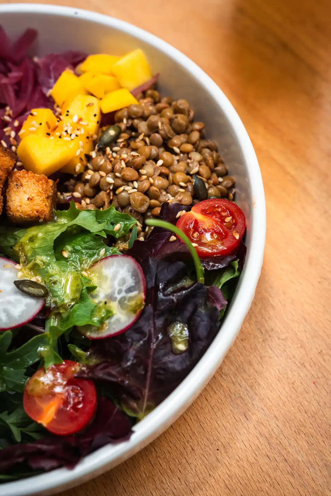 Bol de ensalada de quinoa, lentejas y mango en Morgentau, restaurante vegano en Sant Martí, Barcelona, ideal para un brunch saludable.