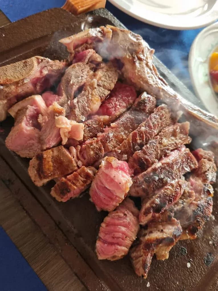 Chuletón a la parrilla en Restaurant Navili, cocina mediterránea en L'Escala, Girona. Disfruta de carnes jugosas con vistas al puerto.