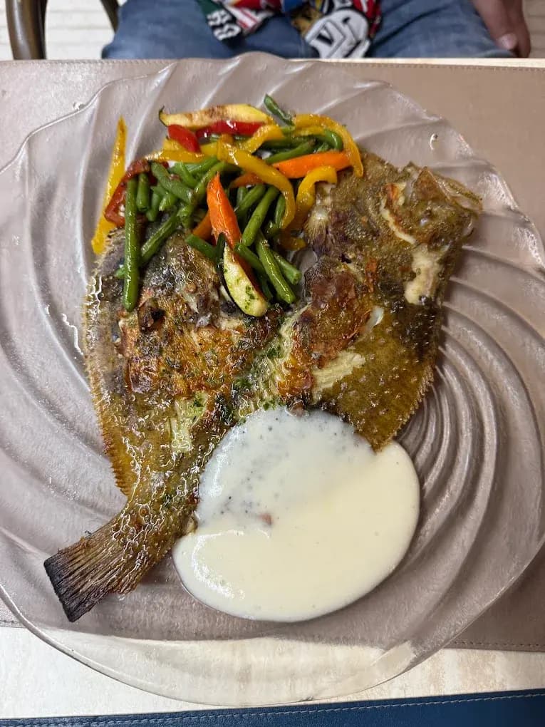 Rodaballo a la plancha con verduras frescas en Restaurant Navili, cocina mediterránea en L'Escala. Disfruta de pescado fresco con vistas al puerto.