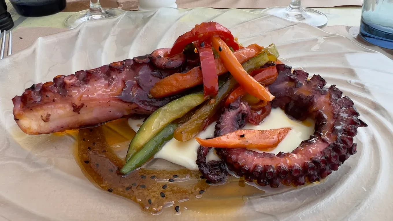 Pulpo a la parrilla con verduras en Restaurant Navili, cocina mediterránea en L'Escala. Disfruta de mariscos frescos frente al puerto.