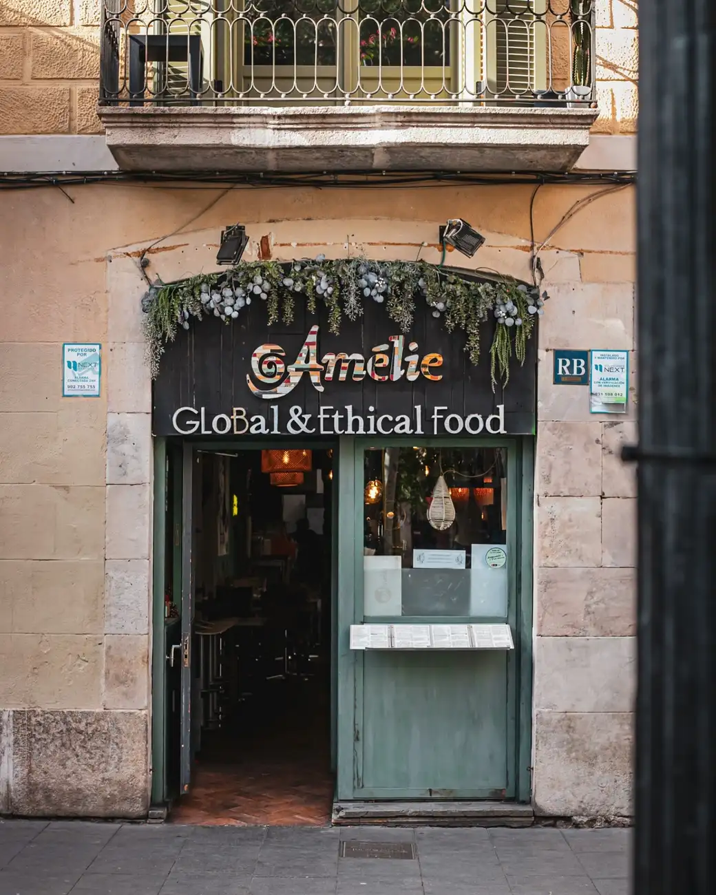 Entrada del Amélie Restaurant en Plaça de la Vila de Gràcia, Barcelona, destacando su enfoque en comida global y ética.