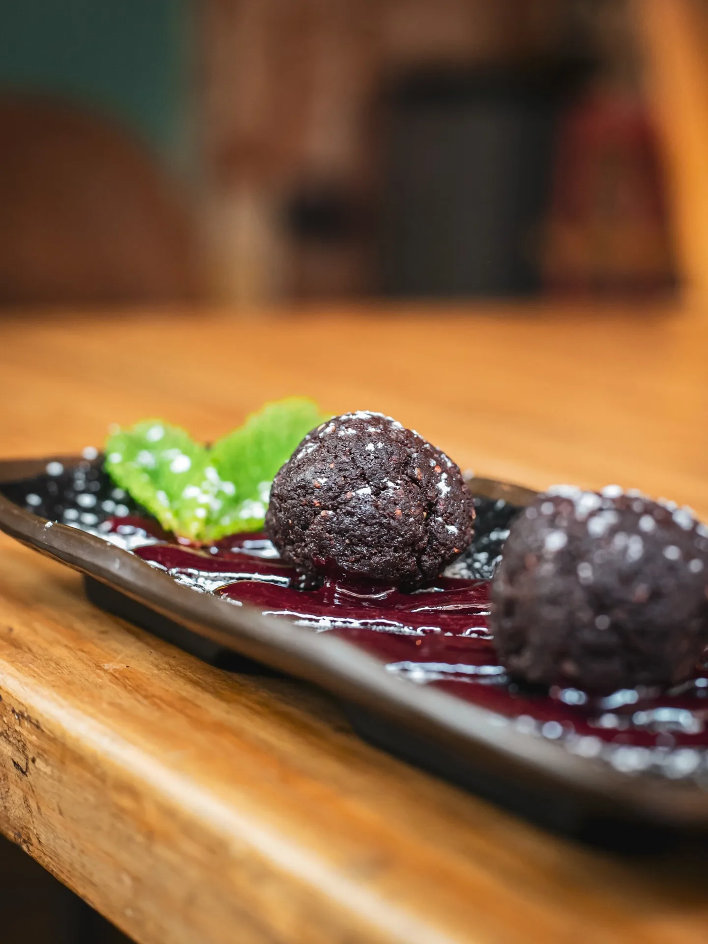 Tapas de autor en Amélie Restaurant, Gràcia, Barcelona: albóndigas de morcilla sobre salsa de frutos rojos, una delicia mediterránea.