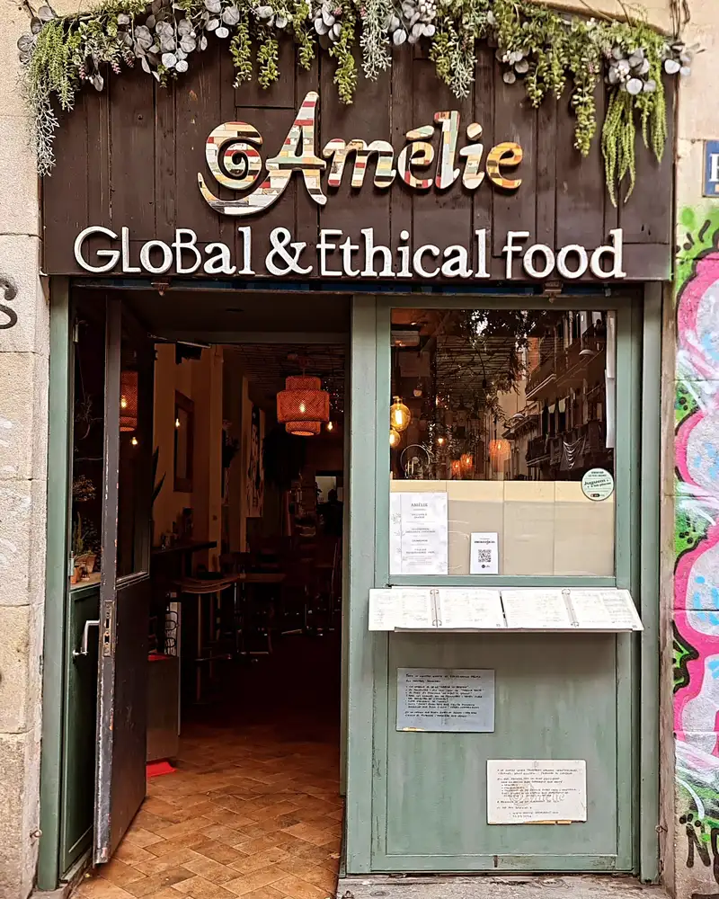 Entrada del Amélie Restaurant en Plaça de la Vila de Gràcia, Barcelona, destacando su enfoque en comida global y ética.