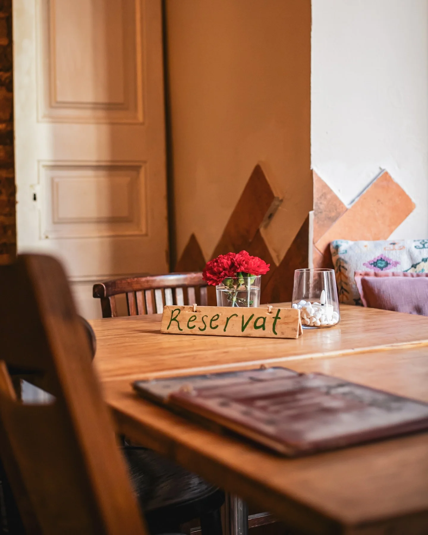 Mesa reservada en el interior de Amélie Restaurant, ubicado en Plaça de la Vila de Gràcia, Barcelona, destacando su ambiente acogedor mediterráneo.