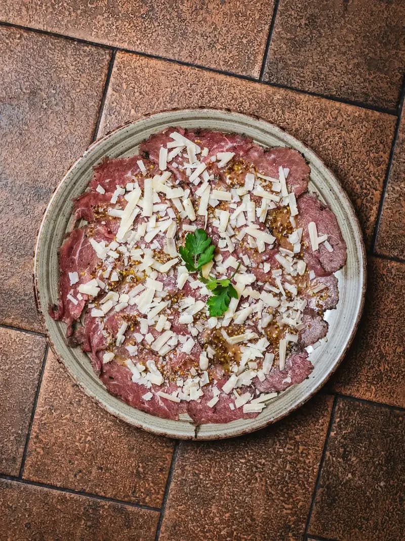 Carpaccio de ternera en Amélie Restaurant, especialidad mediterránea en Plaça de la Vila de Gràcia, Barcelona.