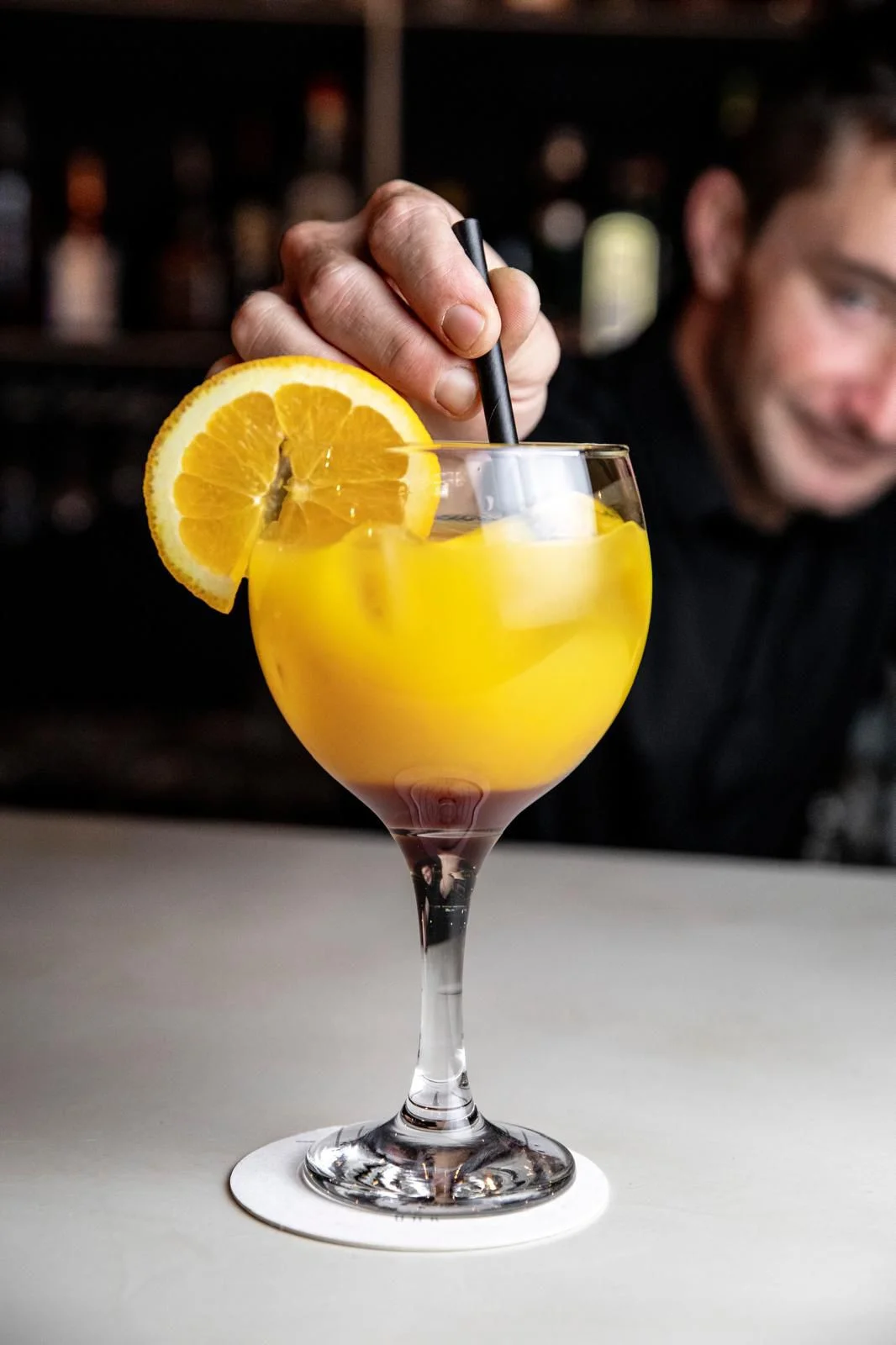 Cóctel creativo servido en Tripti Bar, coctelería de autor en Barcelona, con una rodaja de naranja decorativa.
