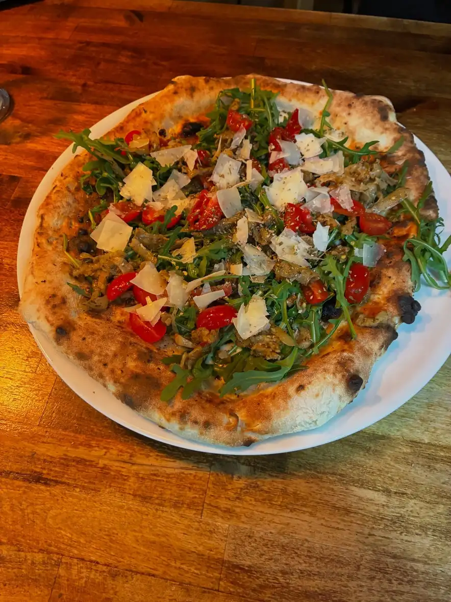 Deliciosa pizza con rúcula y parmesano en Ristorante Il Capriccio Napoletano, auténtica cocina italiana en Sant Martí, Barcelona.