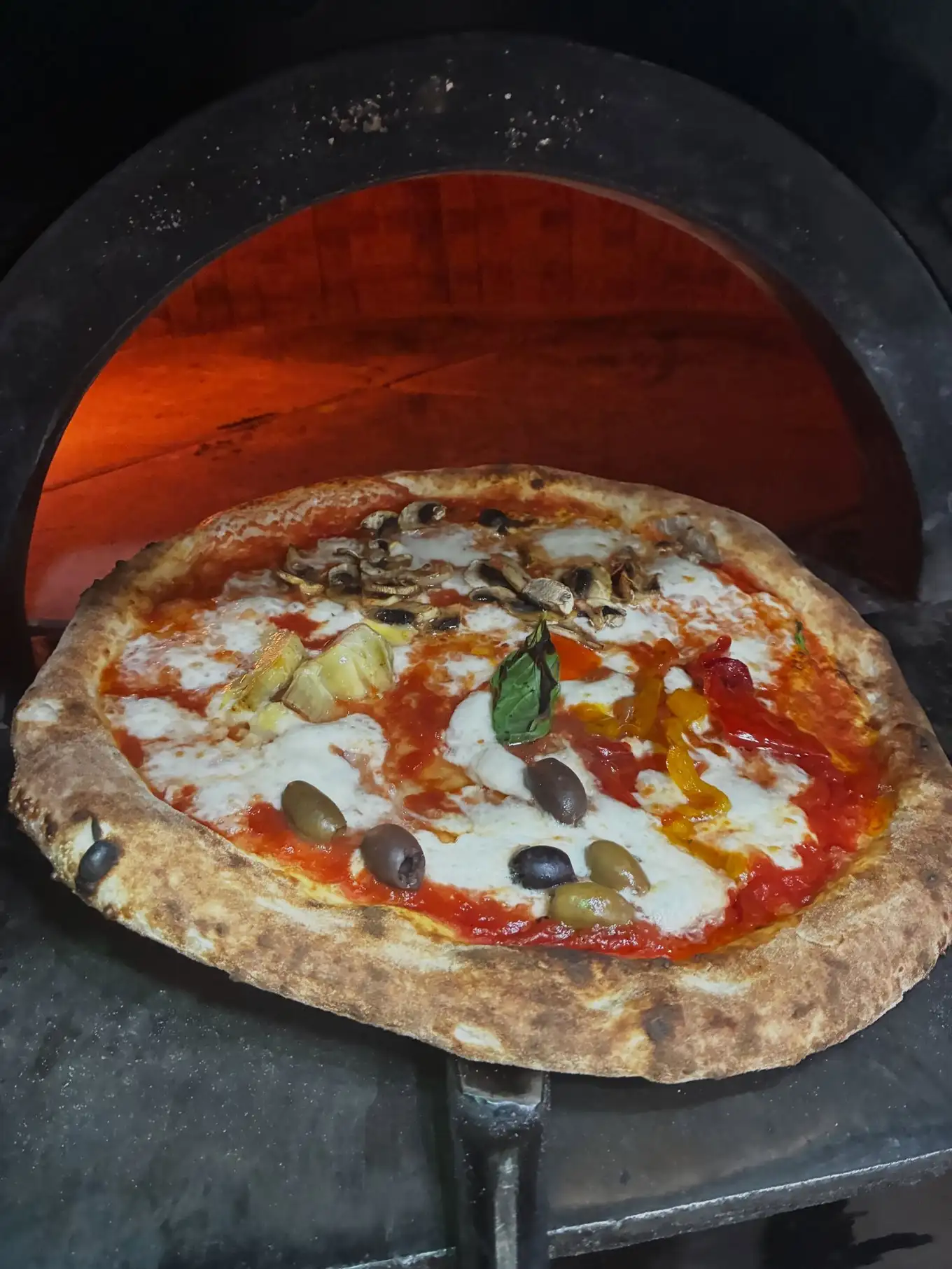 Pizza Capricciosa recién salida del horno en Ristorante Il Capriccio Napoletano, auténtica cocina italiana en Sant Martí, Barcelona.