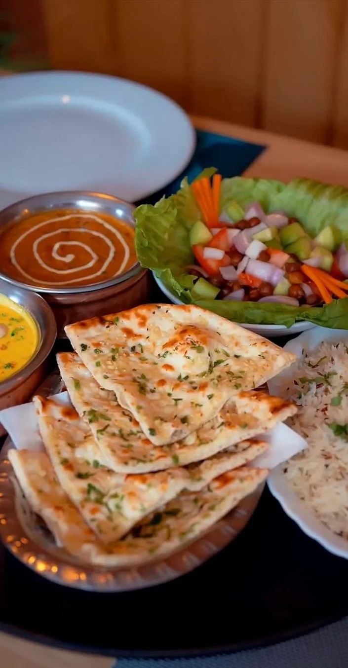 Cheese garlic naan cortado en triángulos con arroz basmati, dal y ensalada fresca en Royal king indian cuisine en Barcelona