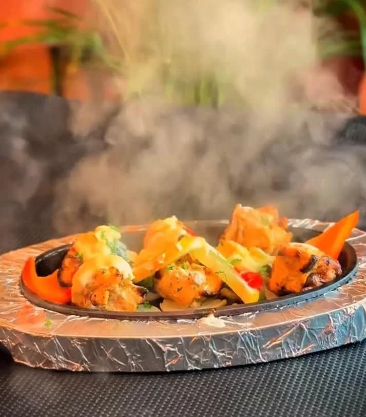 Fuente humeante de tandoori mix grill con trozos de carne marinada servida al hierro caliente en Royal king indian cuisine en Barcelona
