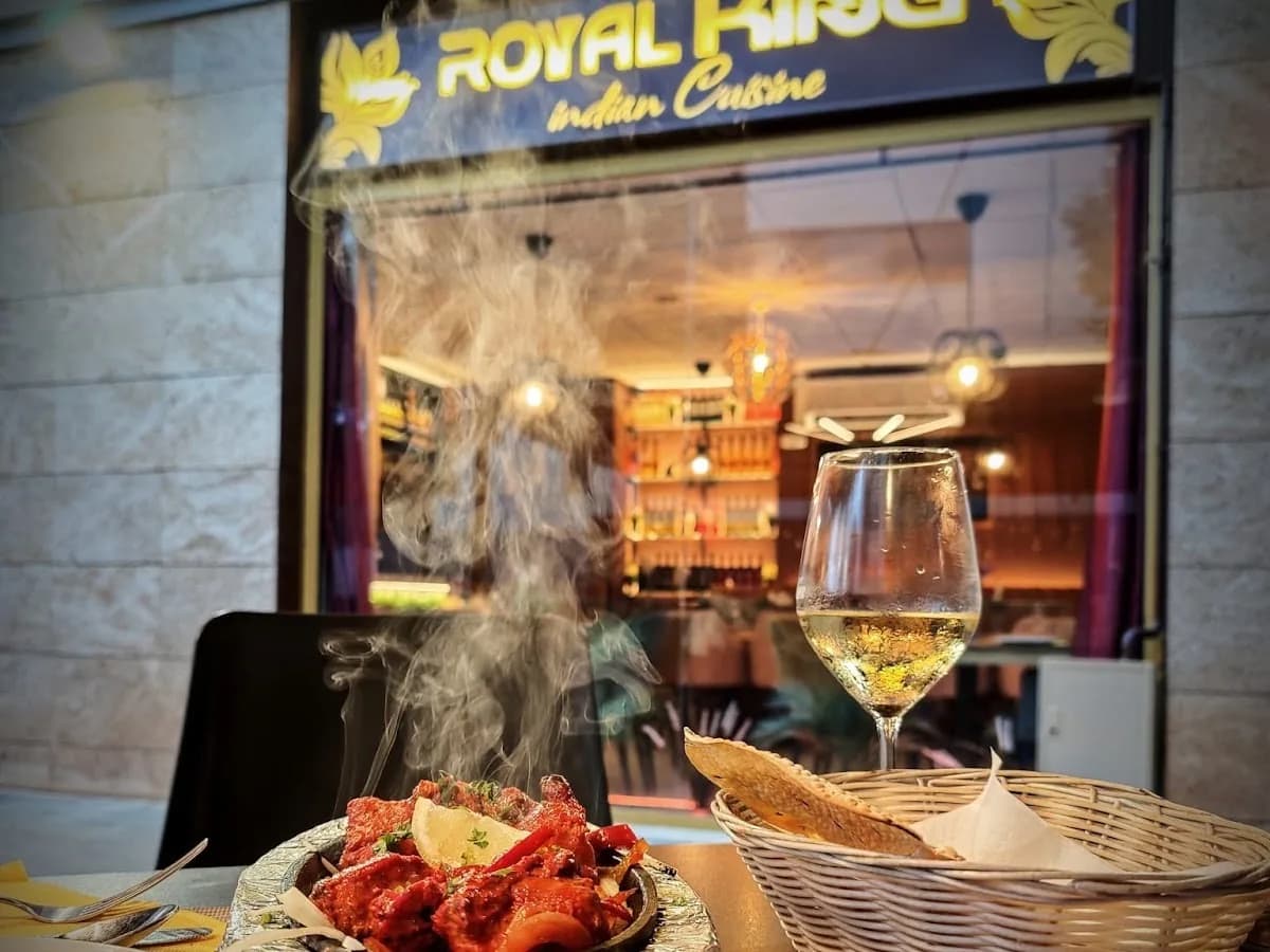 Tandoori Mix Grill humeante en mesa de terraza con copa de vino blanco frente a Royal King indian cuisine en Barcelona