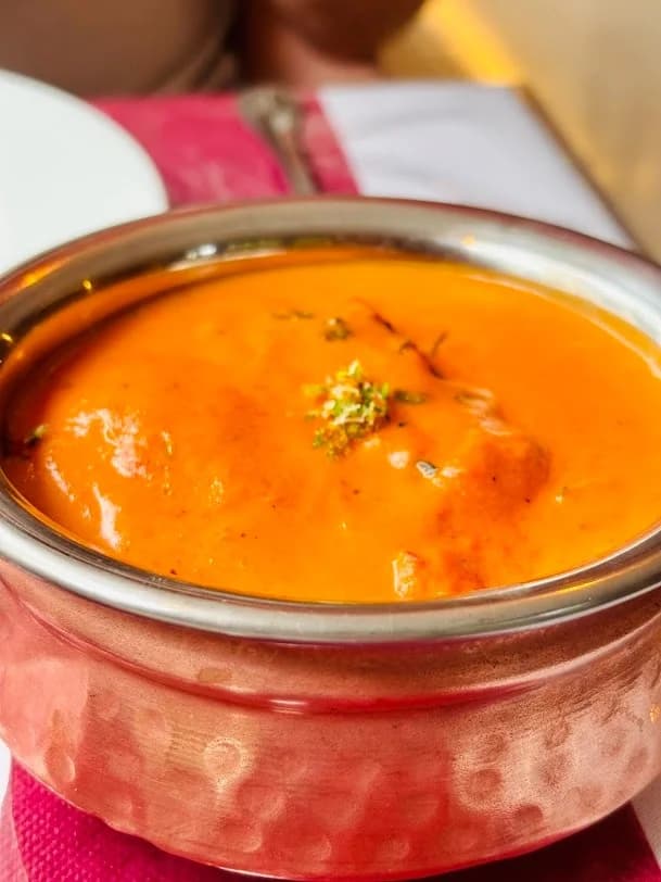 Butter Chicken con salsa cremosa de tomate servido en cuenco de cobre en Royal king indian cuisine en Barcelona