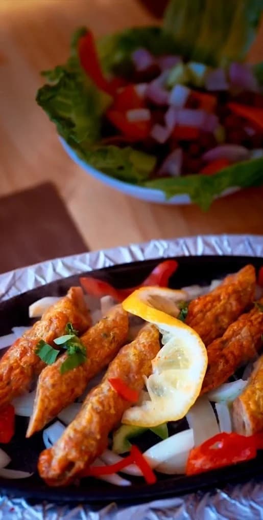 Tandoori Shiekh Kebab de carne sobre cama de cebolla y pimientos en Royal king indian cuisine, restaurante indio en Barcelona