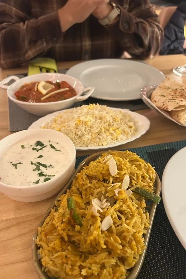 Royal Special Biryani y salsa raita sobre mesa de madera en Royal King Indian Cuisine, restaurante de cocina india en Barcelona