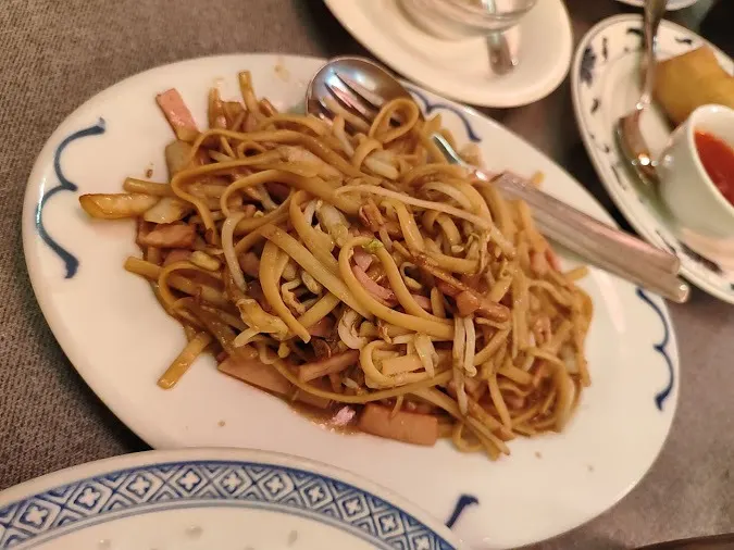 - tallarines chinos salteados con jamón y brotes de soja en plato tradicional
